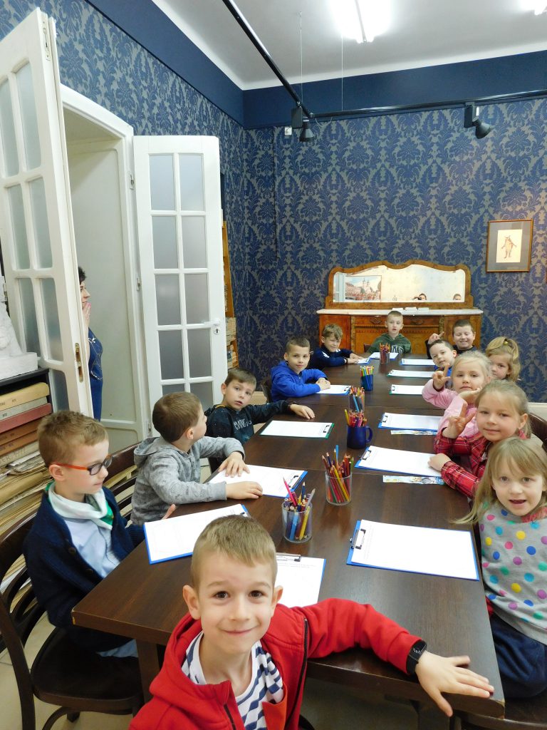 Dzieci siedzą przy stolikach.