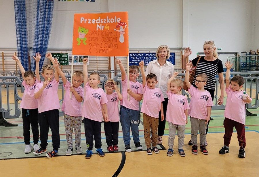 grupka dzieci trzymających tansparent z napisem przedszkole nr 4 wraz z nauczycielkami
