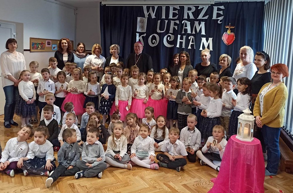 Grupa dzieci pozuje do zdjęcia z nauczycielami i Biskupem Jerzym Mazurem.